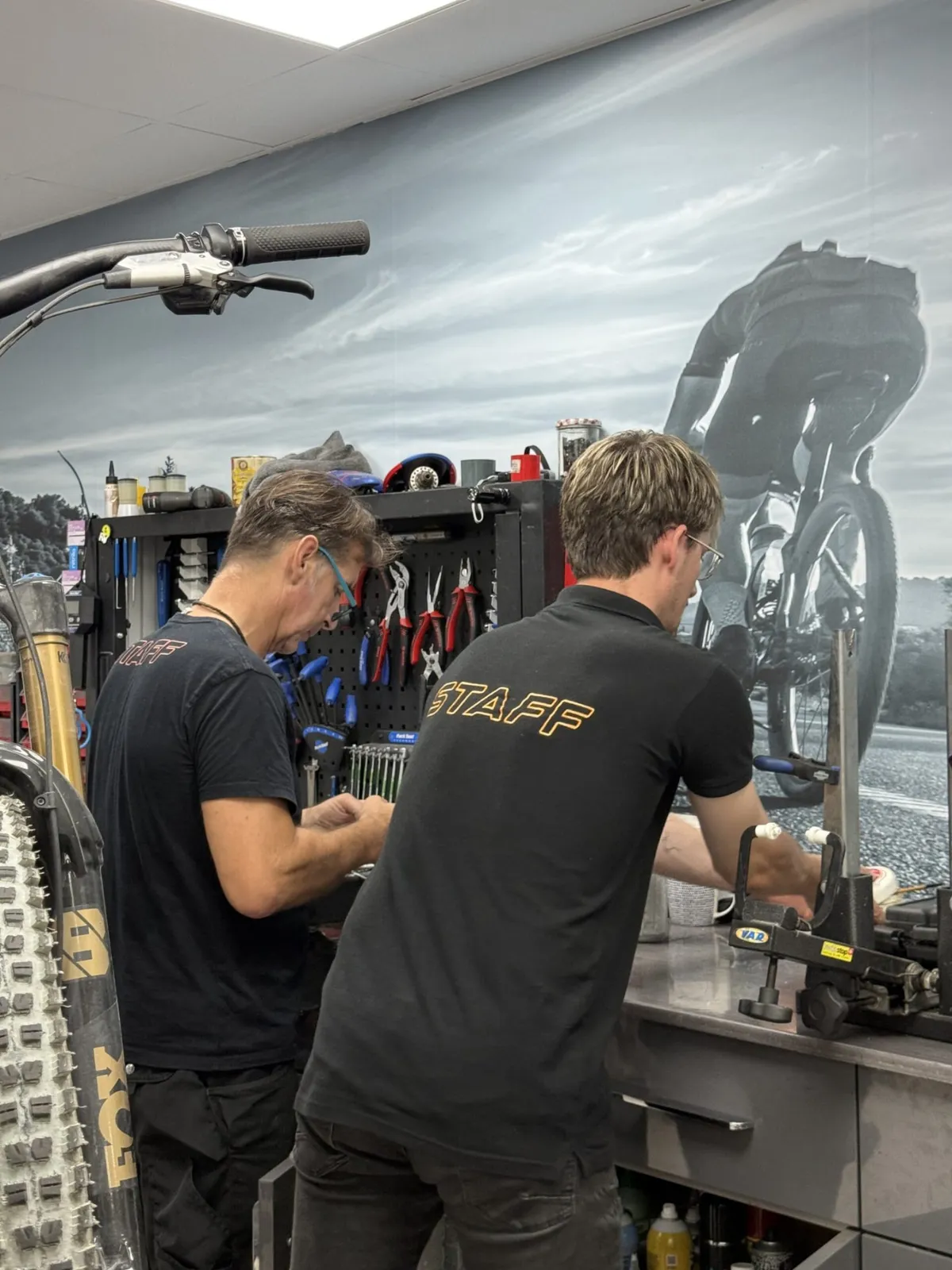 Zwei Mechaniker von Biking Luca arbeiten gemeinsam an einem Fahrrad